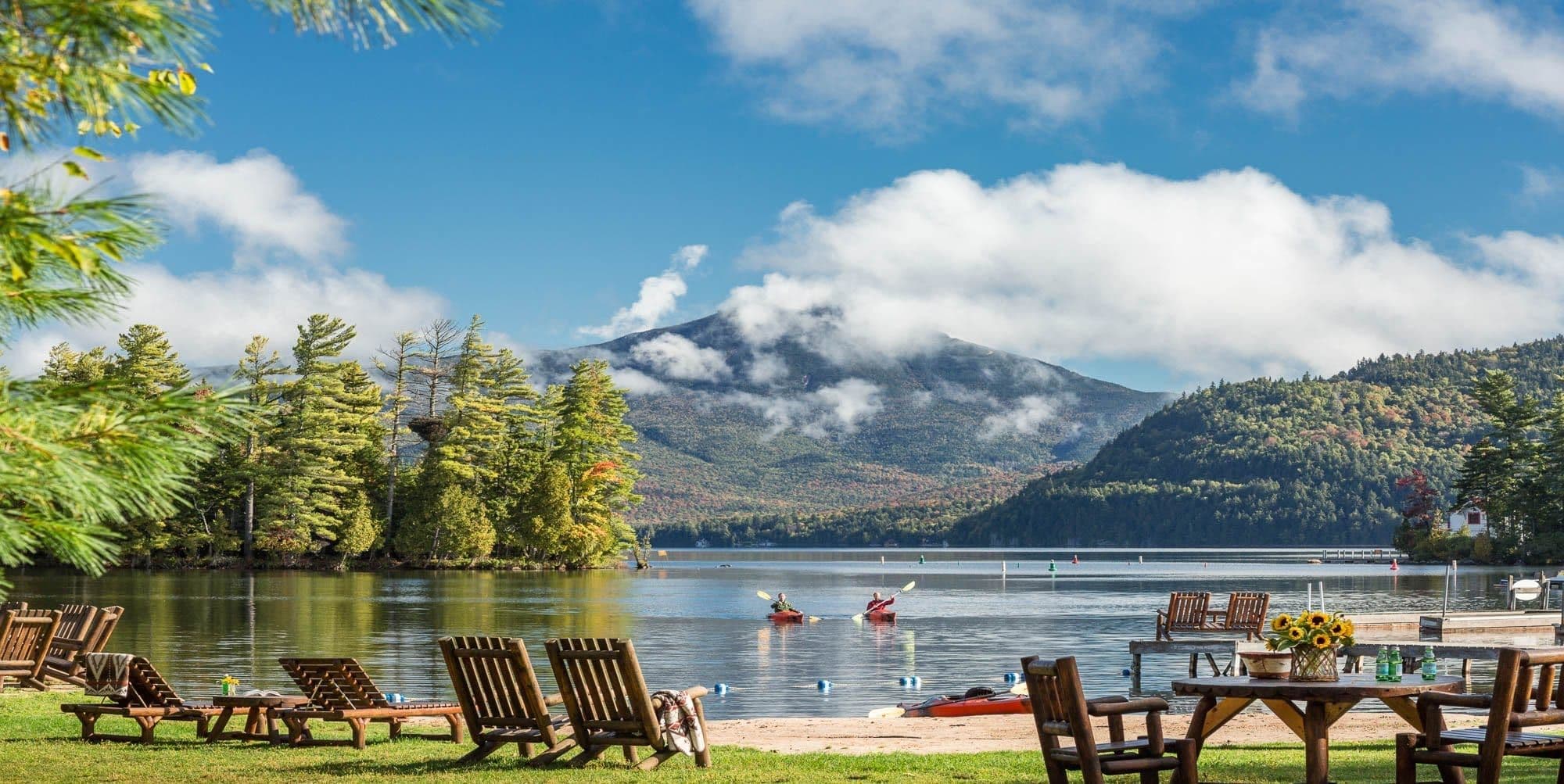 Whiteface Lodge, Lake Placid Adirondack chairs and 2 kayakers in the lake, mountain in the background