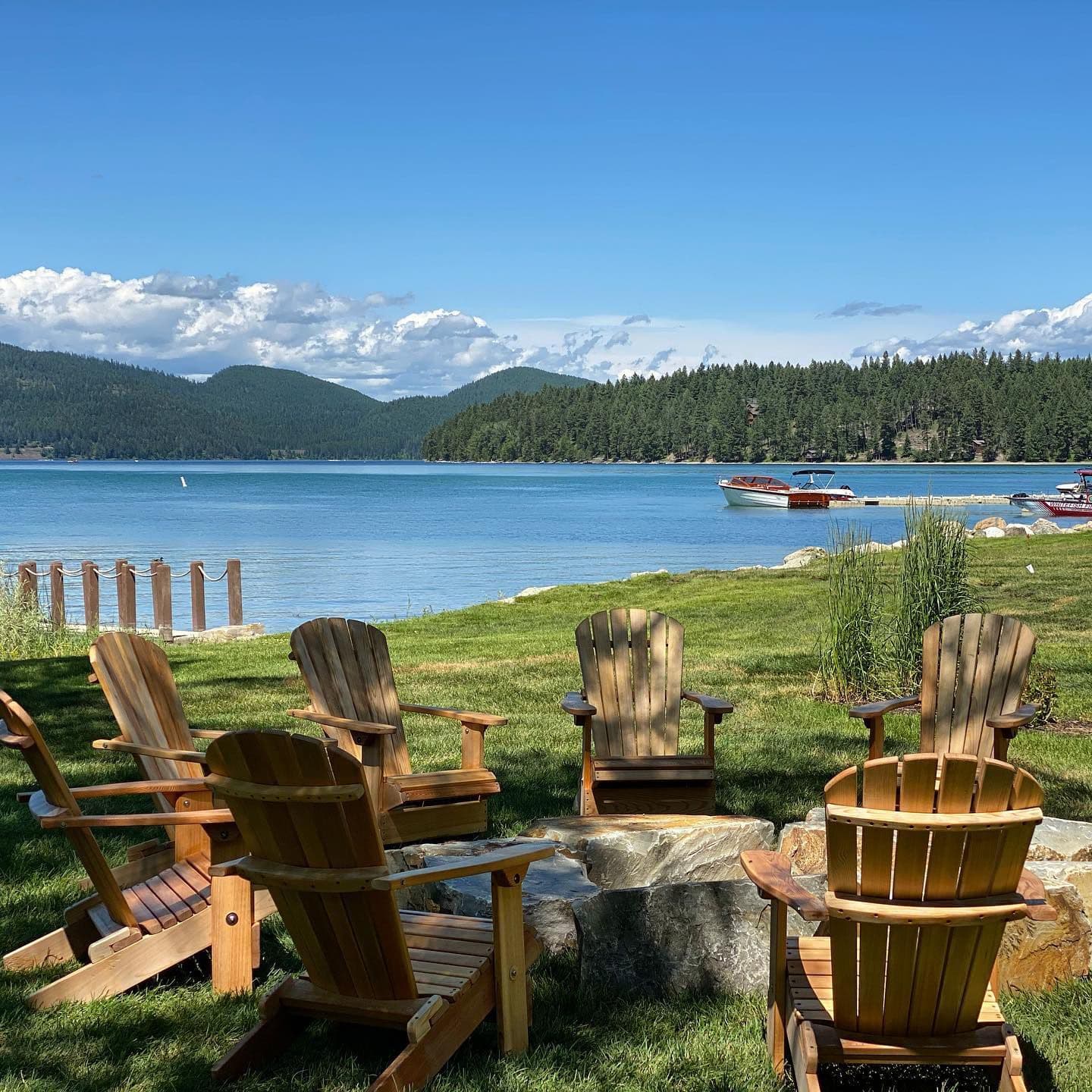 The Lodge at Whitefish lake, Adirondack chairs around a rock campfire overlooking the lake