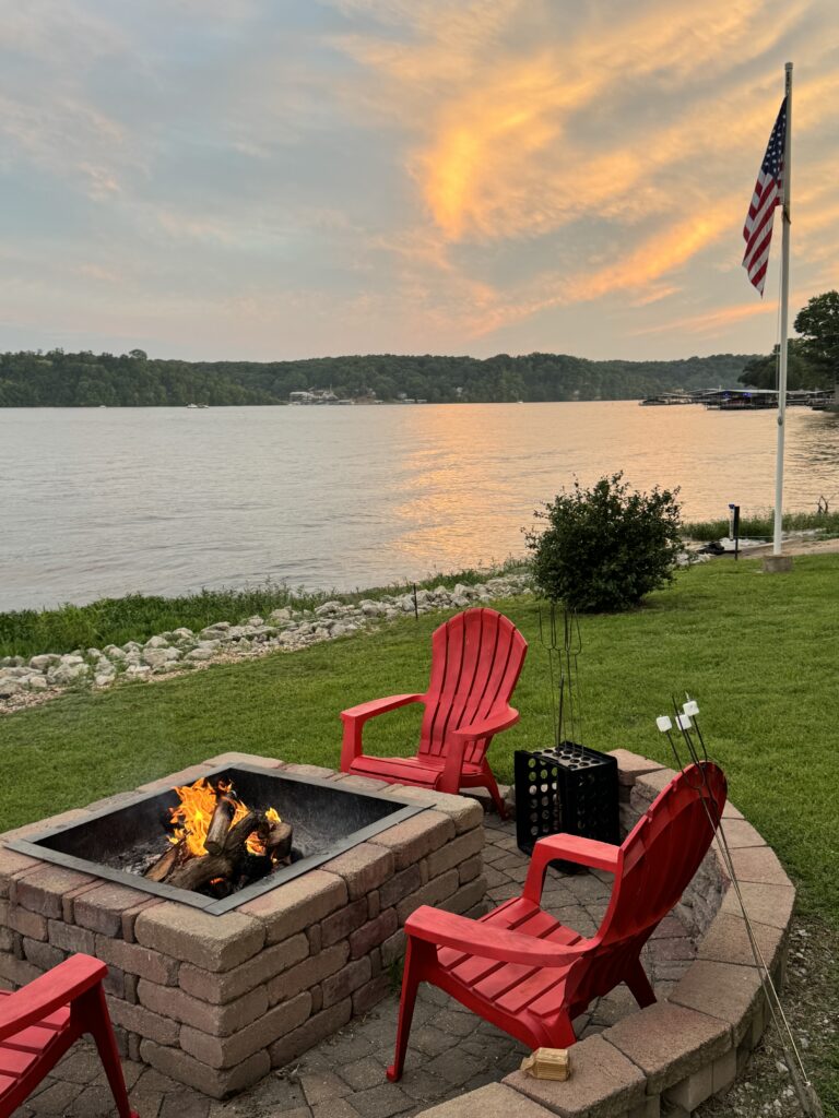 Lake view with Red Adirondack chairs around a fire pit with an American Flagpole in the background