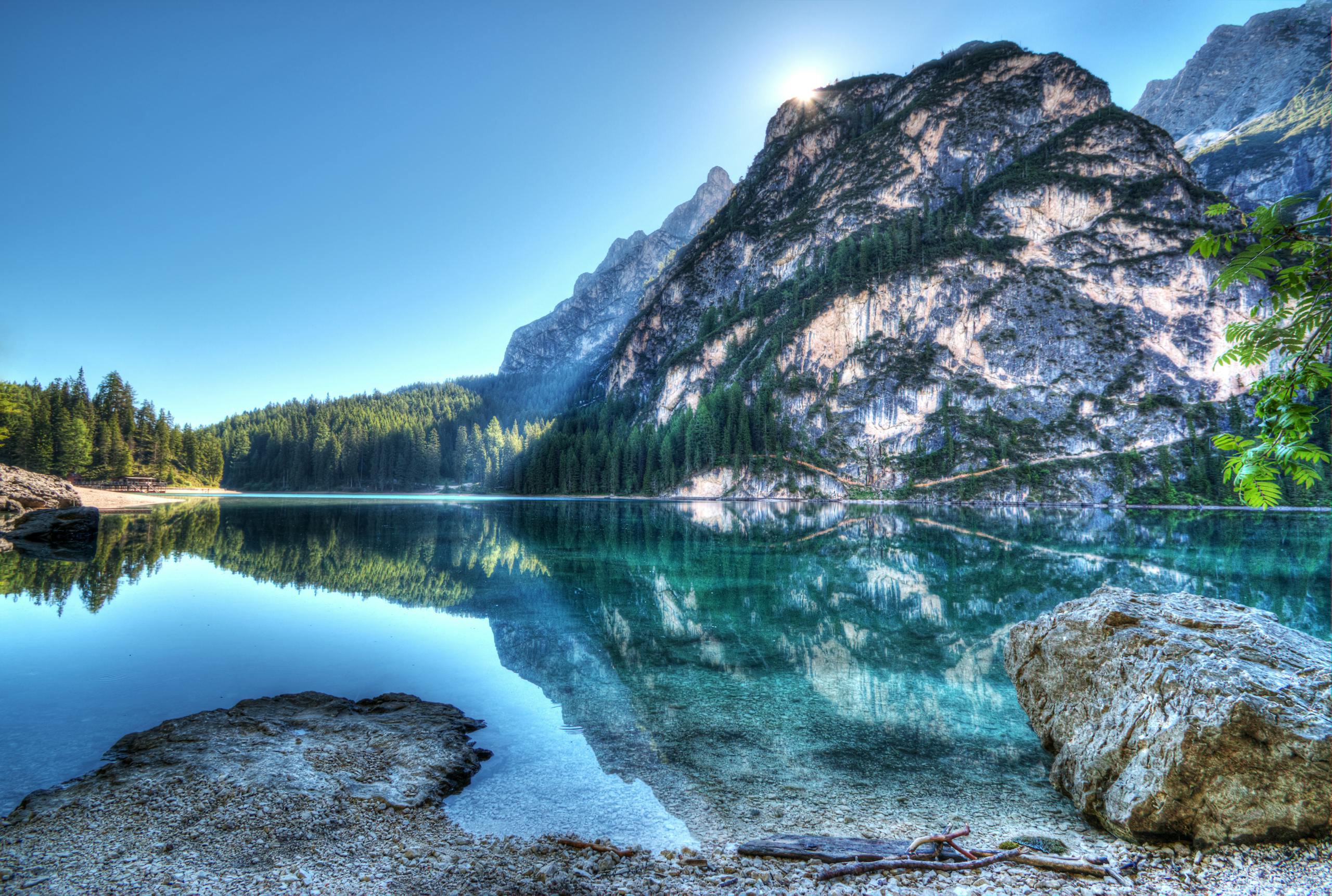 Serene mountain lake with crystal-clear reflections under a bright daytime sky.