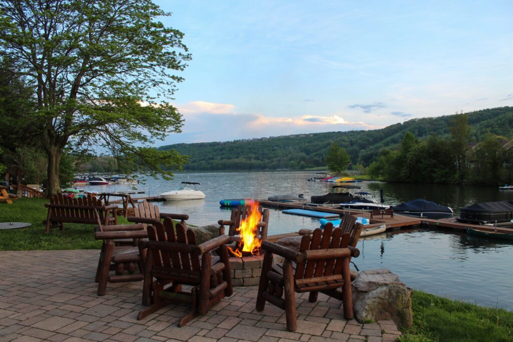 Deep Creek Lake with Wooden chairs around a firepit and docks in the lake with boats and water toys tied up