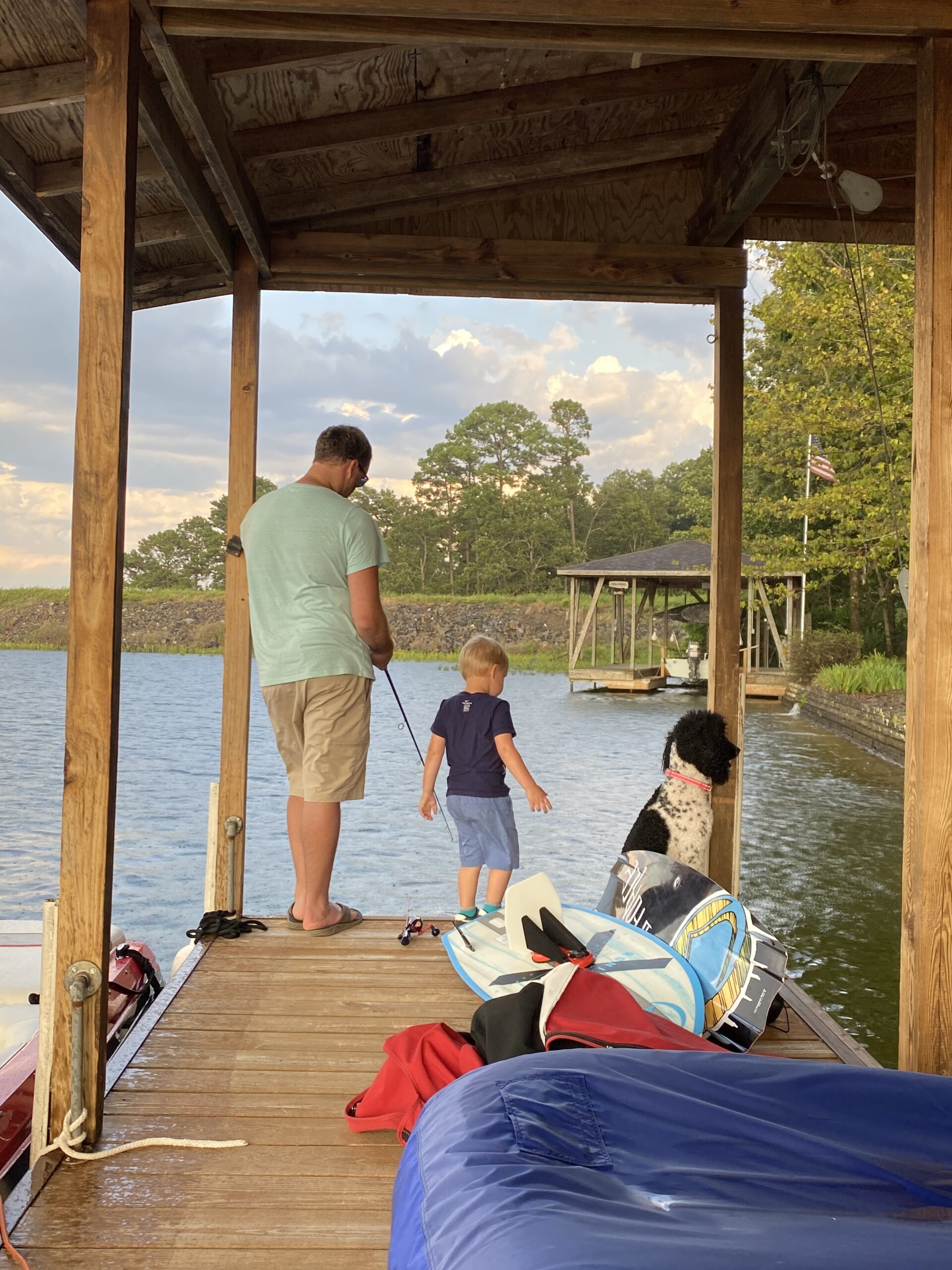 Dad and son with dog fishing on a dock at the lake