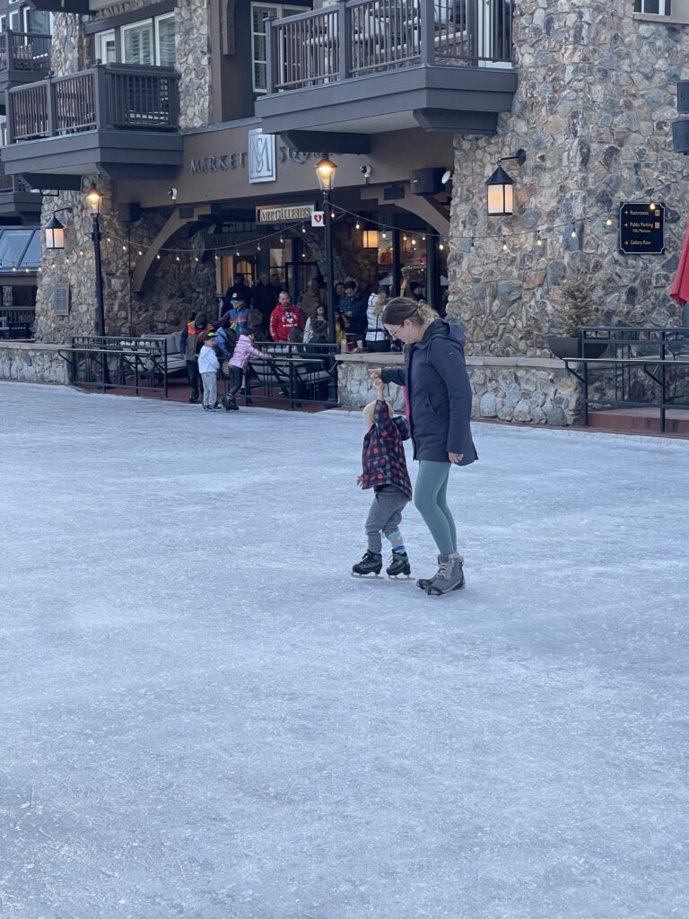 Mom holding sons hand while ice skating