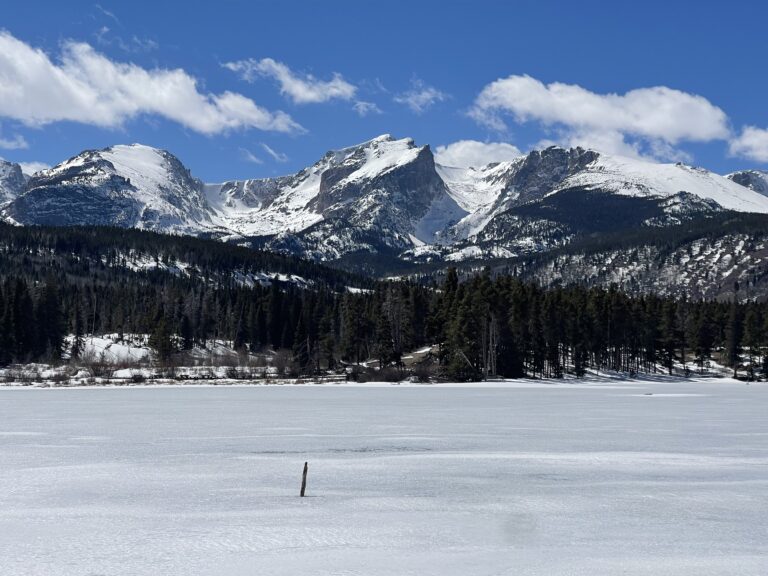 Snow covered and iced over Lake in Colorado with mountains in the background