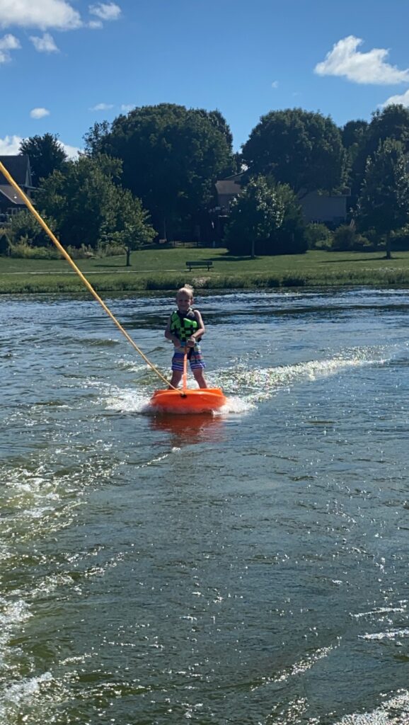 Kid on a wakeboard behind a boat