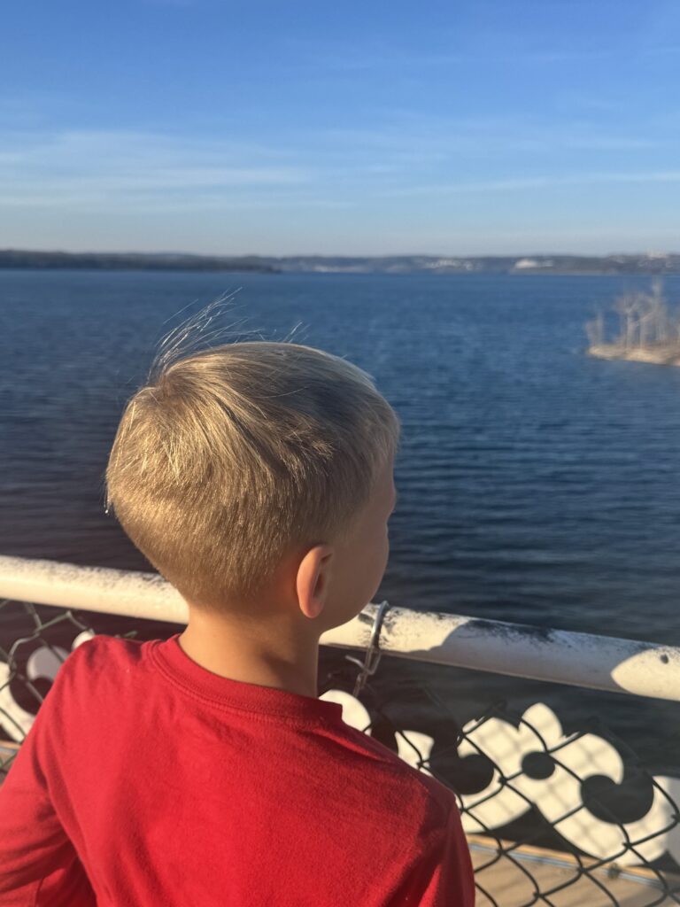 Child in a red shirt looking out over Table Rock Lake in a boat