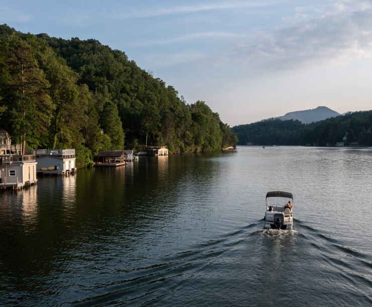 View of Docks and a Pontoon boat driving on Lake Lure