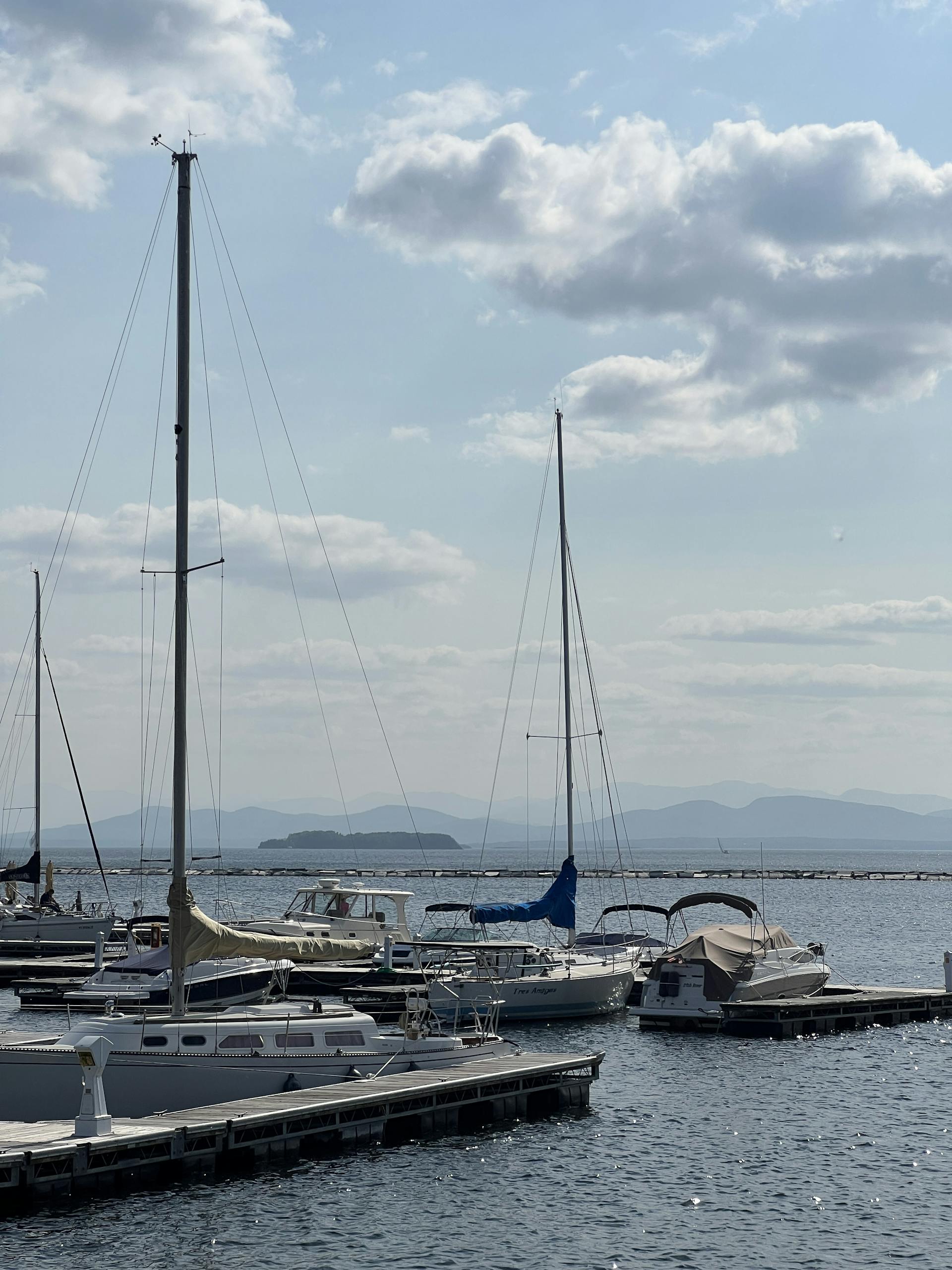 A peaceful scene of sailboats moored in Burlington Harbor on Lake Champlain under a blue sky.