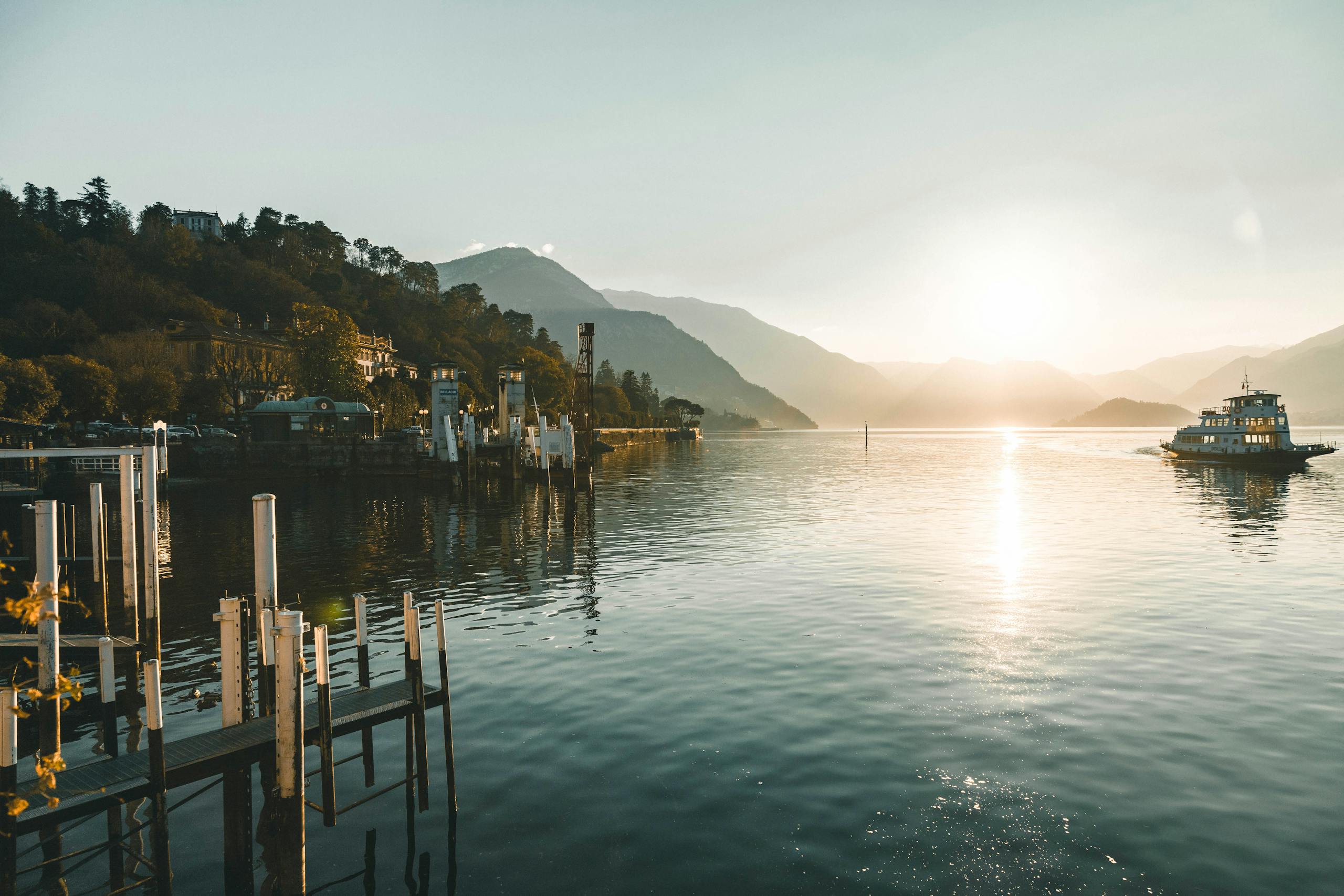 Beautiful sunset over Lake Como with a ferry boat and mountains in the background.