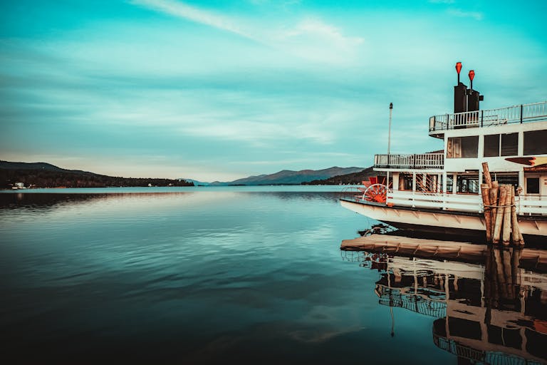 Beautiful view of a paddleboat on Lake George with a serene sunset backdrop. Ideal for nature and travel enthusiasts.