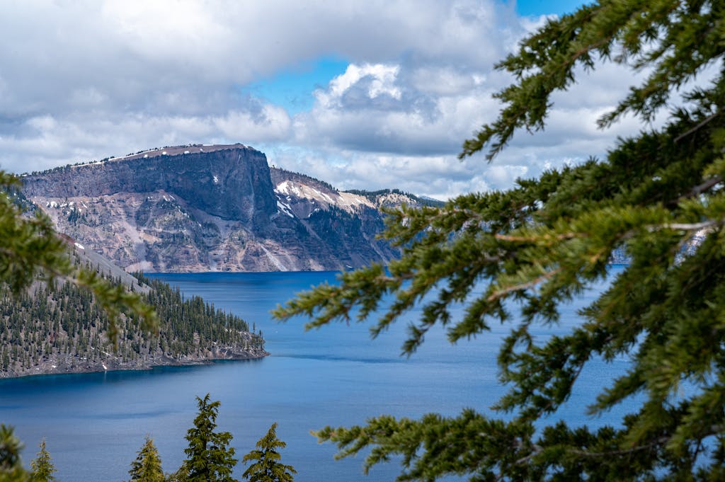 Breathtaking view of Crater Lake surrounded by evergreen trees under a bright summer sky.