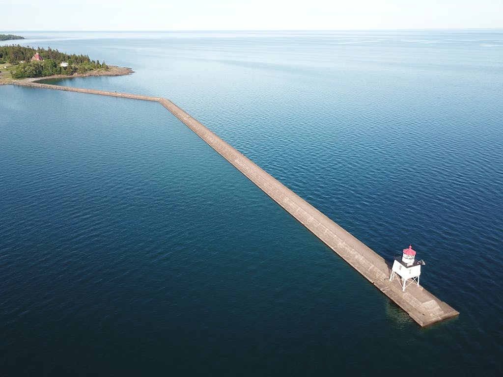 Drone shot of the Lake County pier extending into Lake Superior with a lighthouse at its tip.