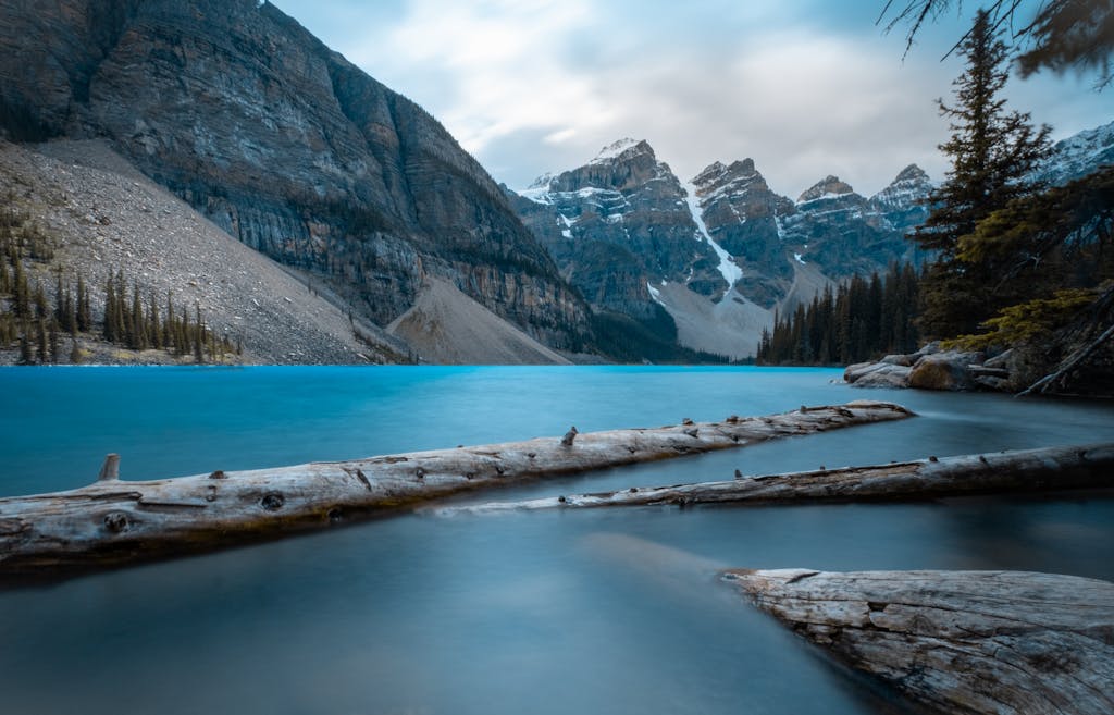 Peaceful Lake Louise surrounded by majestic mountains and serene nature at sunset.