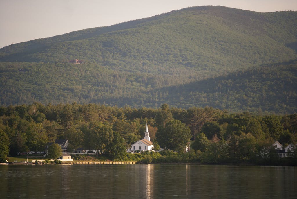 Picturesque church by a lake with mountain backdrop in Tuftonboro, New Hampshire.