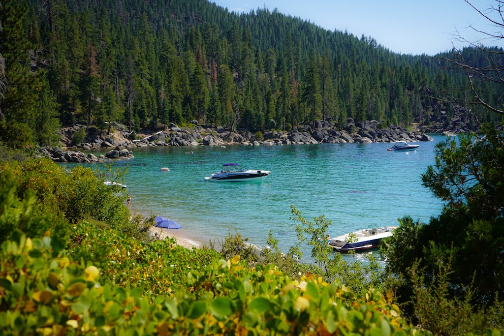 Serene landscape featuring boats on Lake Tahoe's clear water and lush green forests. Perfect for travel and nature enthusiasts.