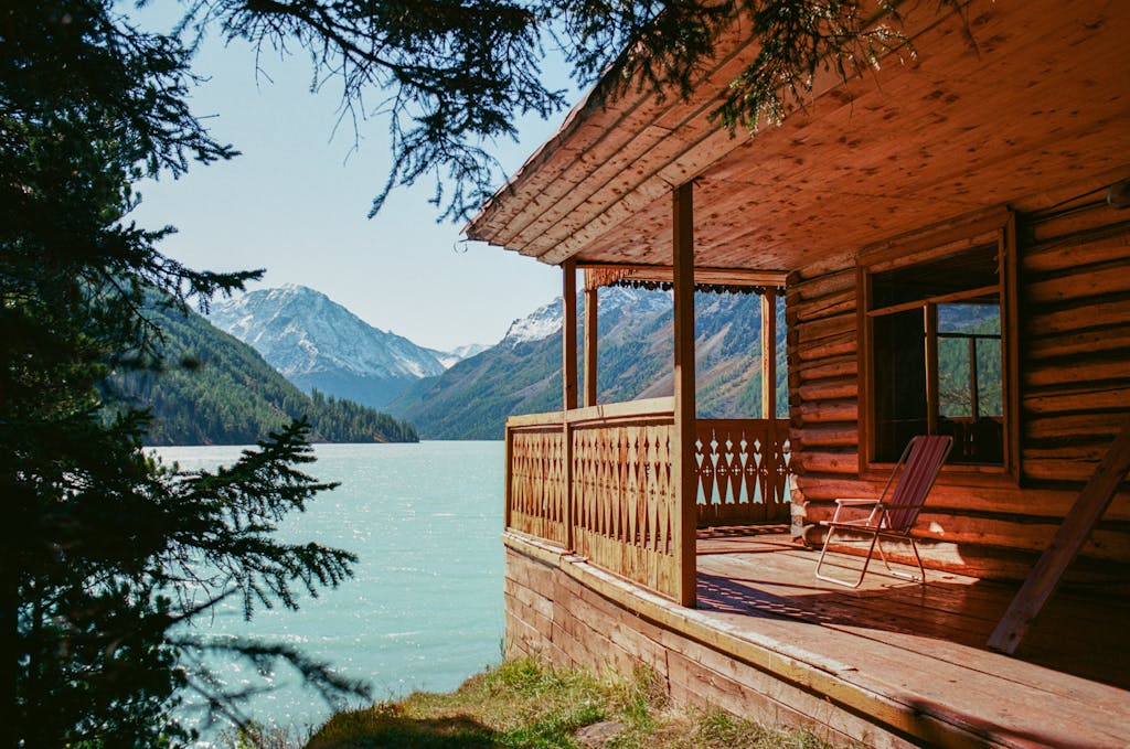 Tranquil scene of a wooden cabin overlooking a serene mountain lake, surrounded by lush forest.