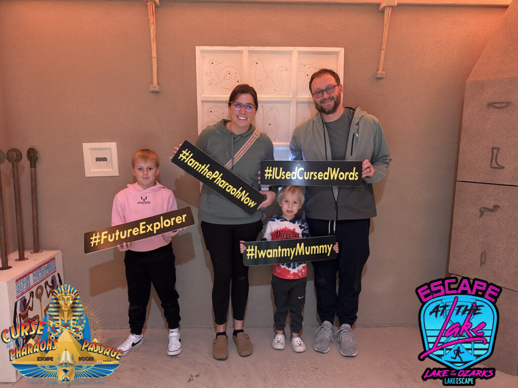 Family holding up hashtag signs after completing Lake Escape Curse of Pharaohs passage game