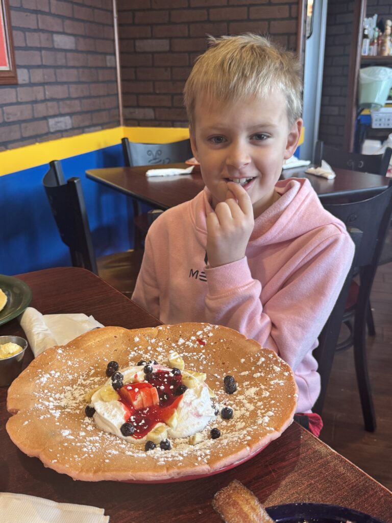 Boy with pink Messi Hoodie with shocked face in front of giant pancake