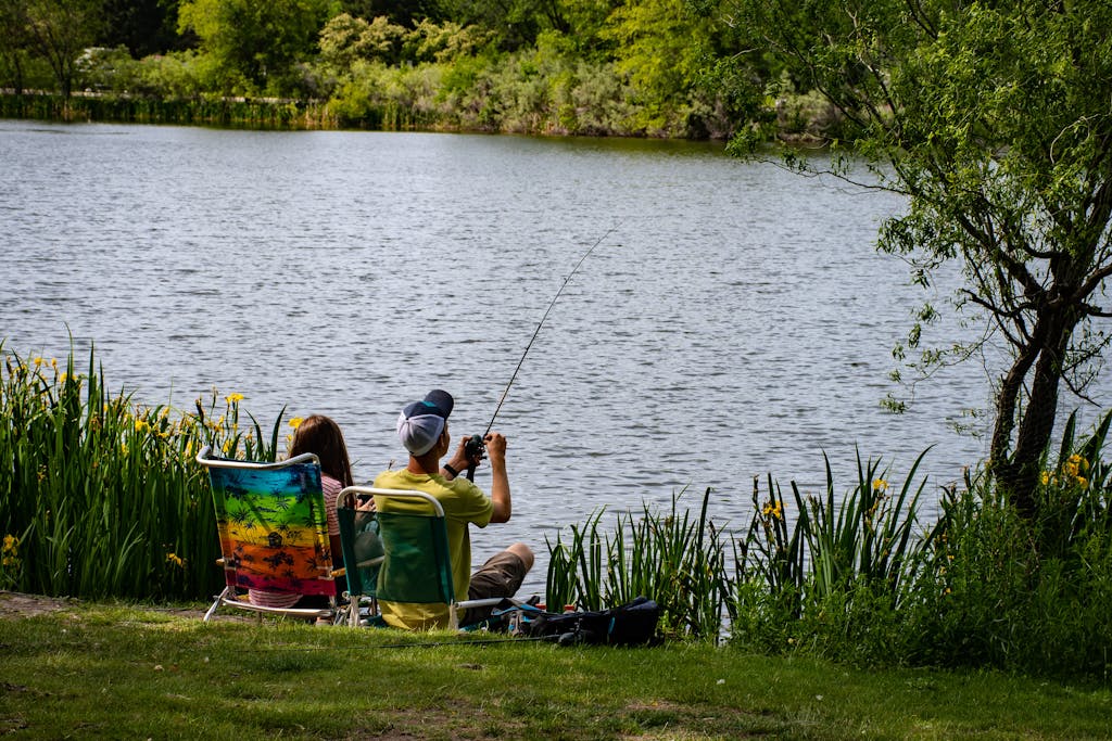 A couple enjoys a peaceful fishing day by a serene lake during summer.