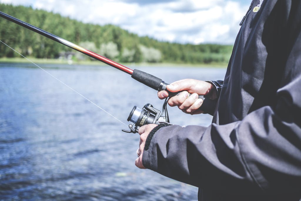 A man enjoys fishing at a lake, showcasing a relaxed outdoor hobby in nature.