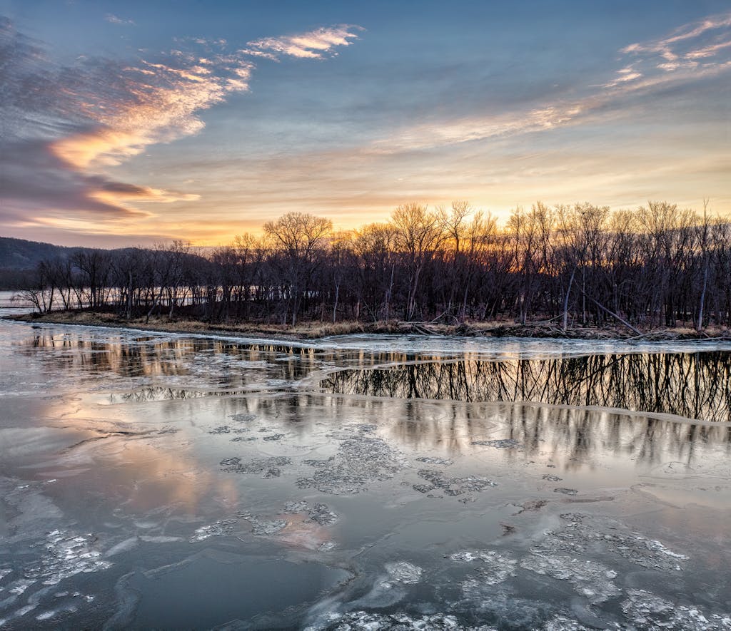 Beautiful sunset over an icy lake and bare trees in West Newton, Minnesota, USA.