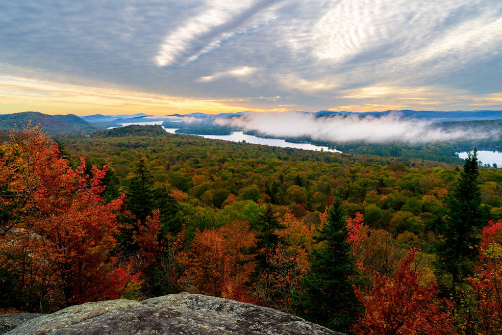 Breathtaking overlook of fall foliage and misty lakes in Adirondack Mountains, New York.