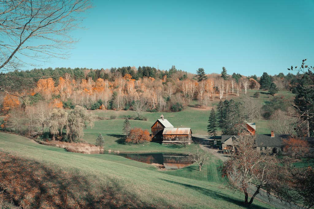 Captivating autumn landscape featuring a classic farmhouse and barn in the rural countryside of Woodstock, Vermont.