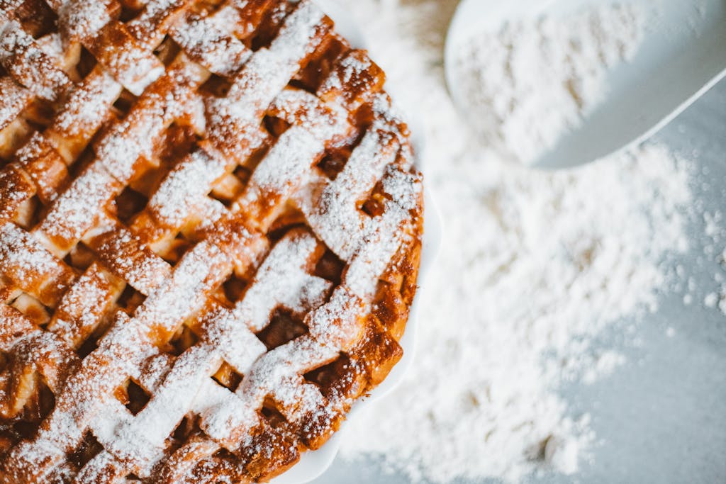 Close-up of a lattice-top apple pie dusted with powdered sugar, perfect for indulgence.