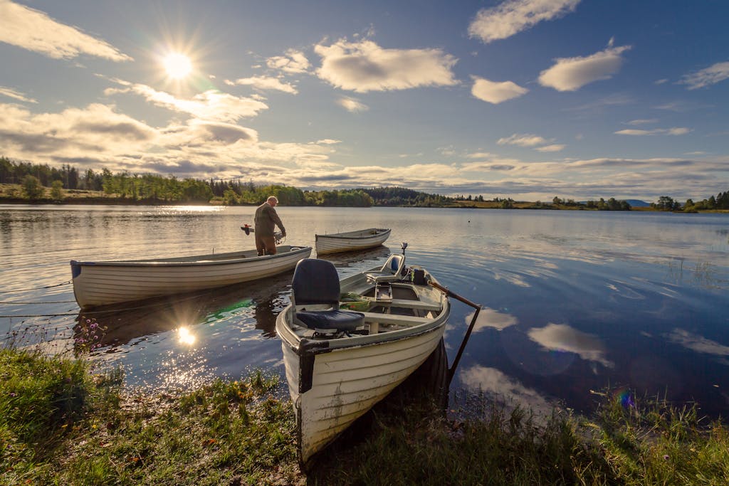 Peaceful sunrise over Stirling Lake, with boats and a fisherman creating scenic reflections.