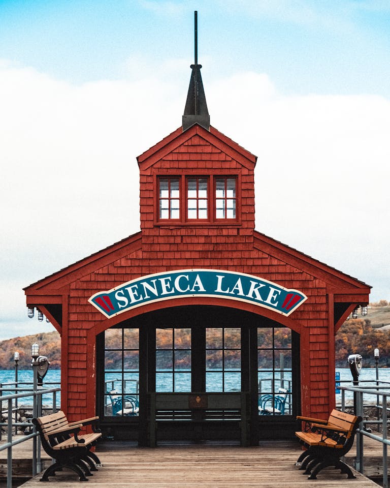 Scenic view of the iconic red pavilion on Seneca Lake dock with benches and blue waters.