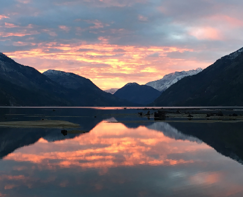 Lake Chelan at sunset with pink and purple sky reflecting off the water and surrounded by mountains