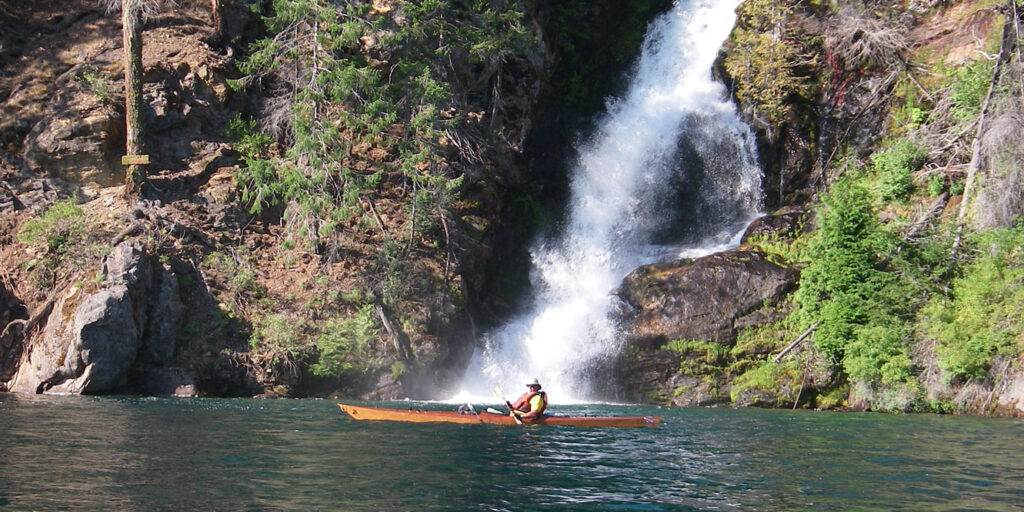 Kayaker in front of a waterfall near Stehekin